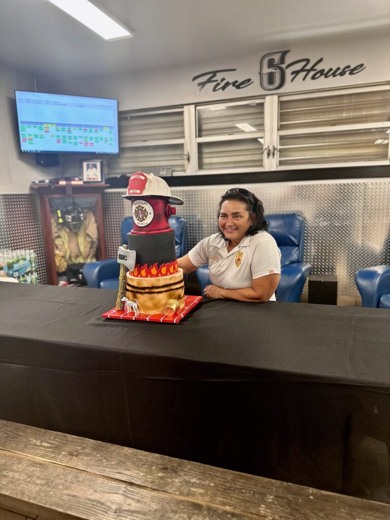 Chief Yoly Alvarez Miami Fire Department first Hispanic female district chief fire officer retirement cake created by Luxe Layers Cakery in Miami Florida featuring sculpted fire hydrant firefighter helmet and Miami Fire Rescue emblem.