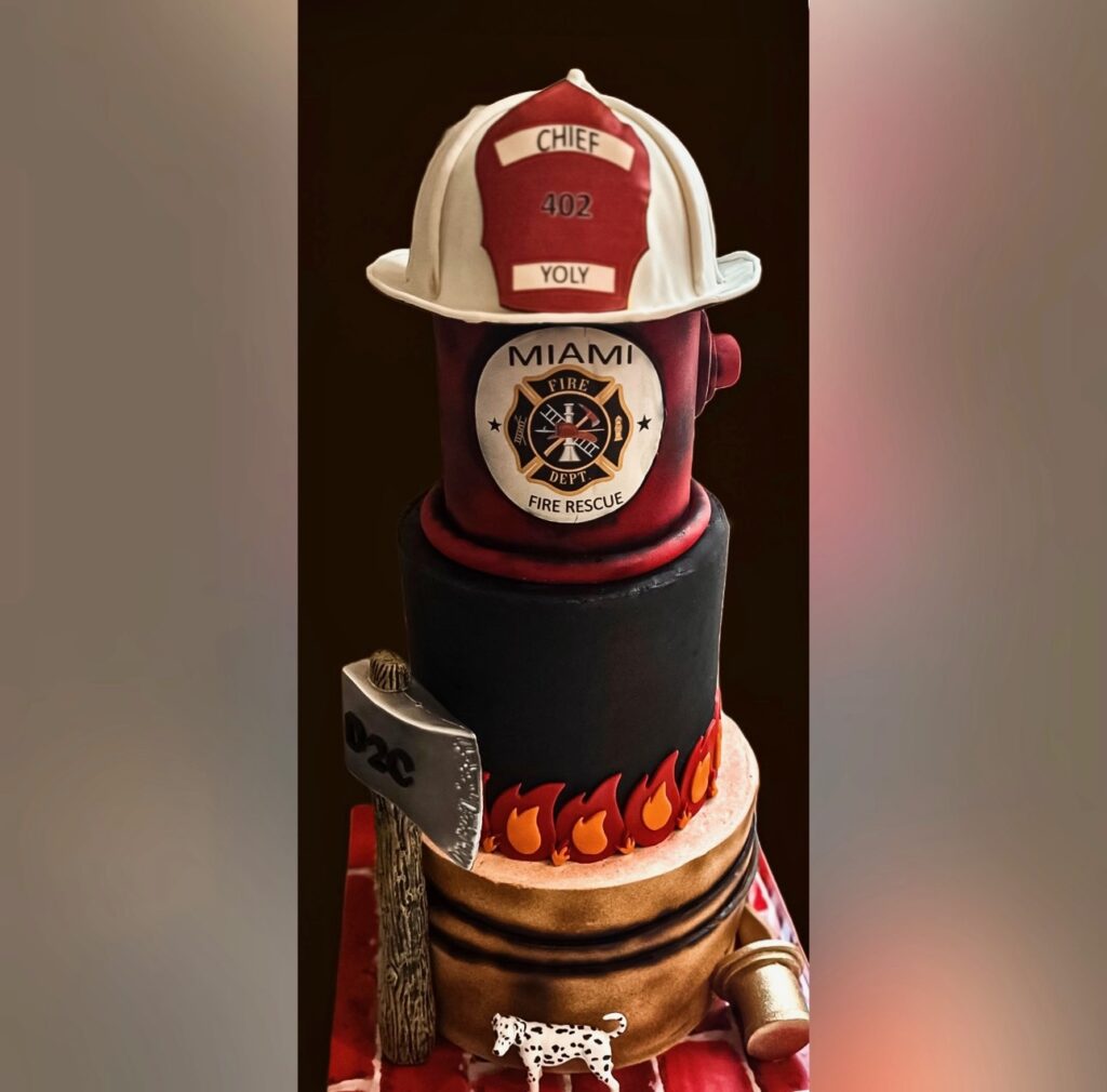 Custom firefighter retirement tribute cake with sculpted fire hydrant, personalized helmet topper, Miami Fire Rescue emblem, and flame accents created by Luxe Layers Cakery in Miami Florida for Chief Yoly Alvarez retirement celebration.