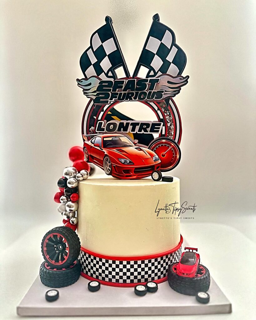 Race car themed birthday cake with sports car topper, checkered flags and tire decorations made by Luxe Layers Cakery in Miami Florida