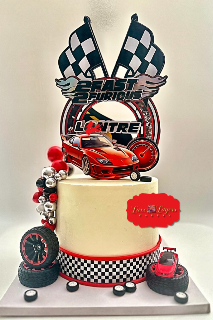 Race car themed birthday cake with sports car topper, checkered flags and tire decorations made by Luxe Layers Cakery in Miami Florida