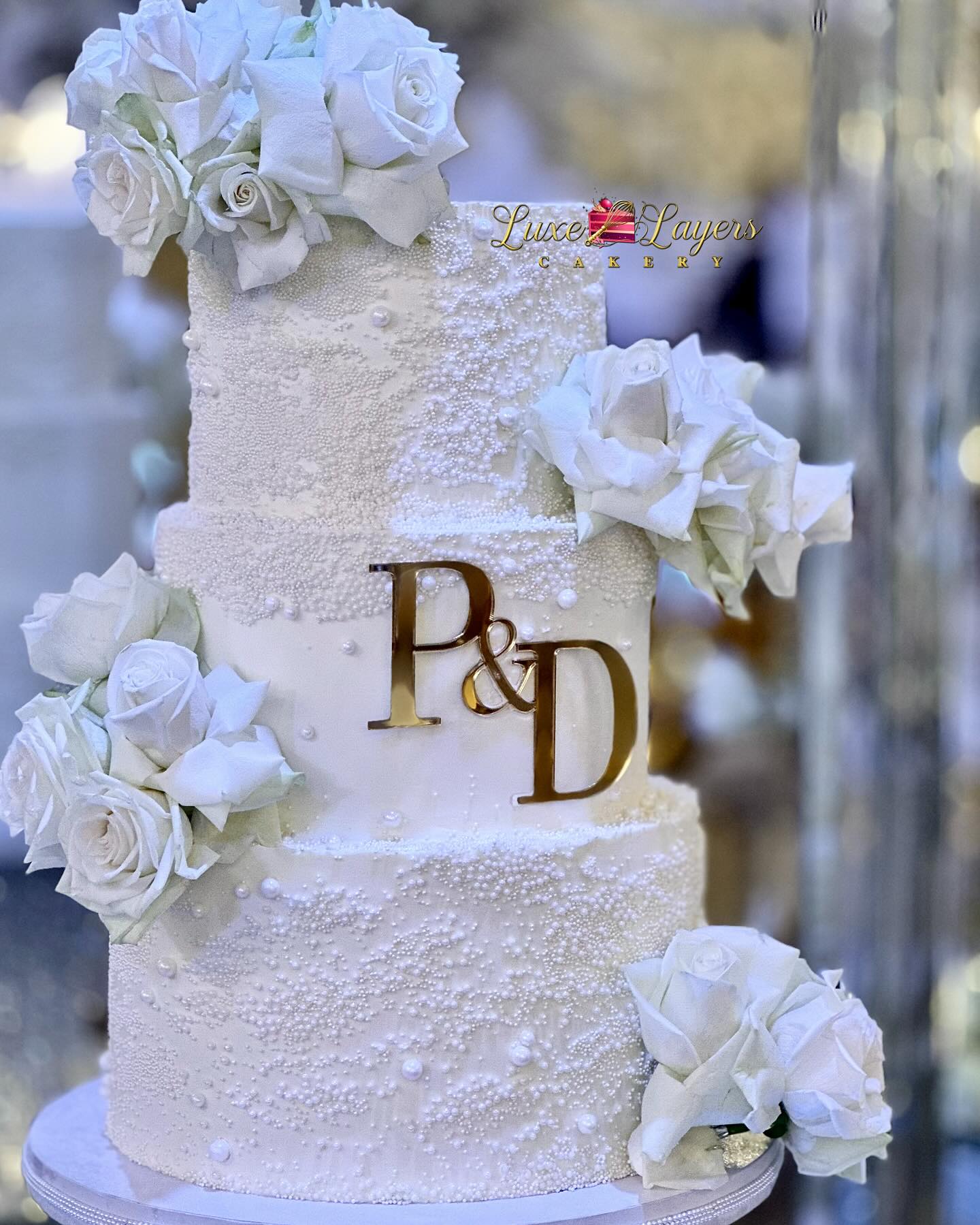 Close-up detail of multi-tier white wedding cake with textured buttercream finish, cascading florals, and individual pearl accents created by Luxe Layers Cakery in Miami Florida