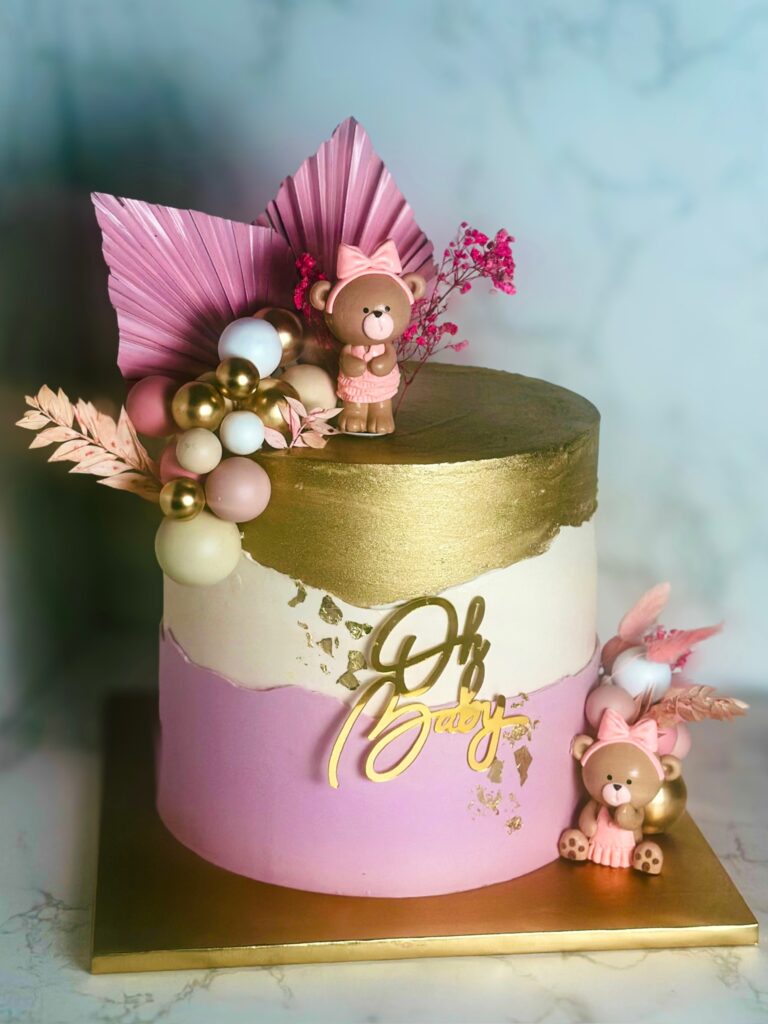 Modern baby shower cake with gold-painted top tier, blush pink and white color blocking, teddy bear toppers, decorative spheres, dried florals, and Oh Baby topper, created by Luxe Layers Cakery in Miami, Florida