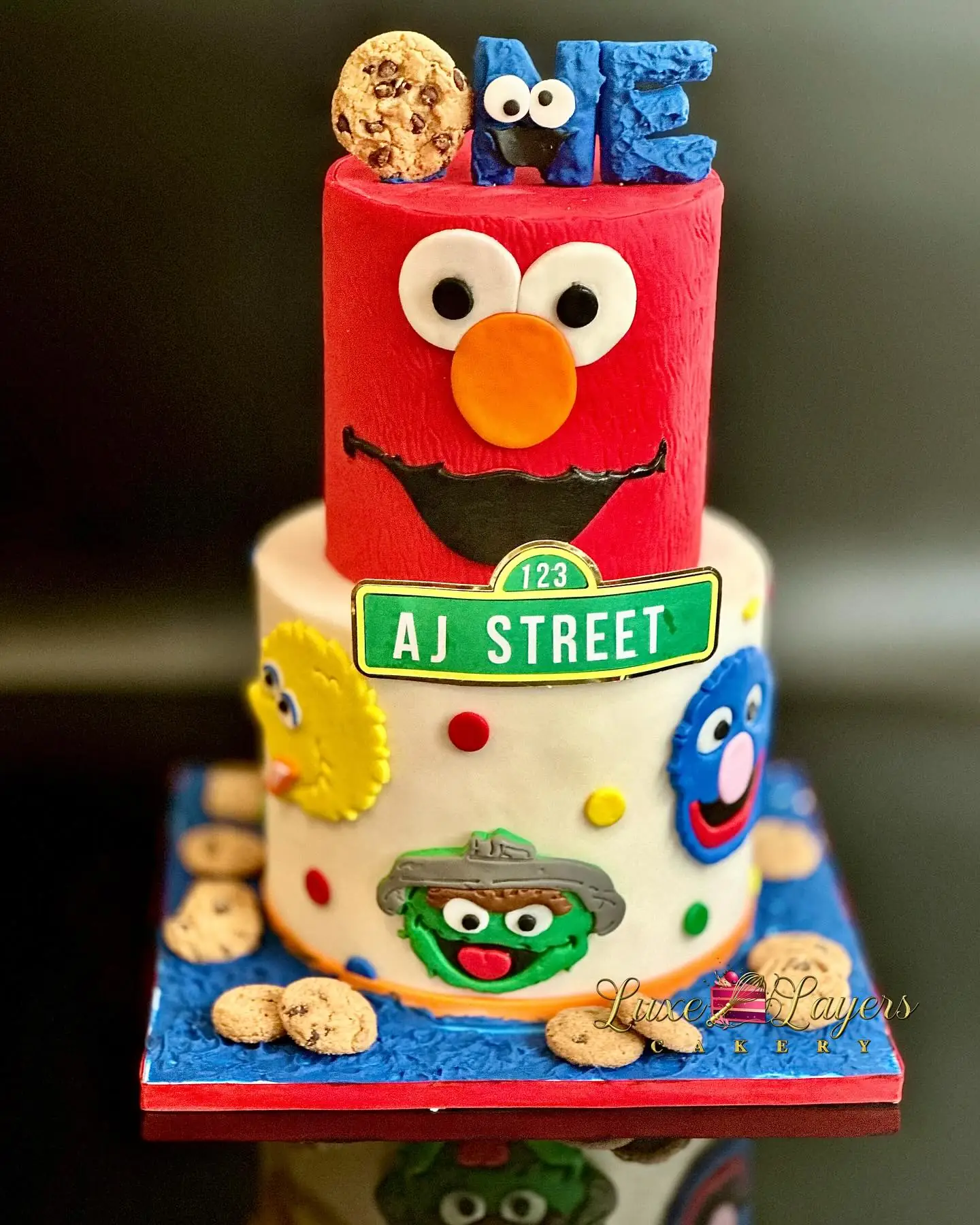 Red, blue, and yellow character-themed first birthday cake with fondant accents and milestone topper — kids birthday cakes Miami by Luxe Layers Cakery