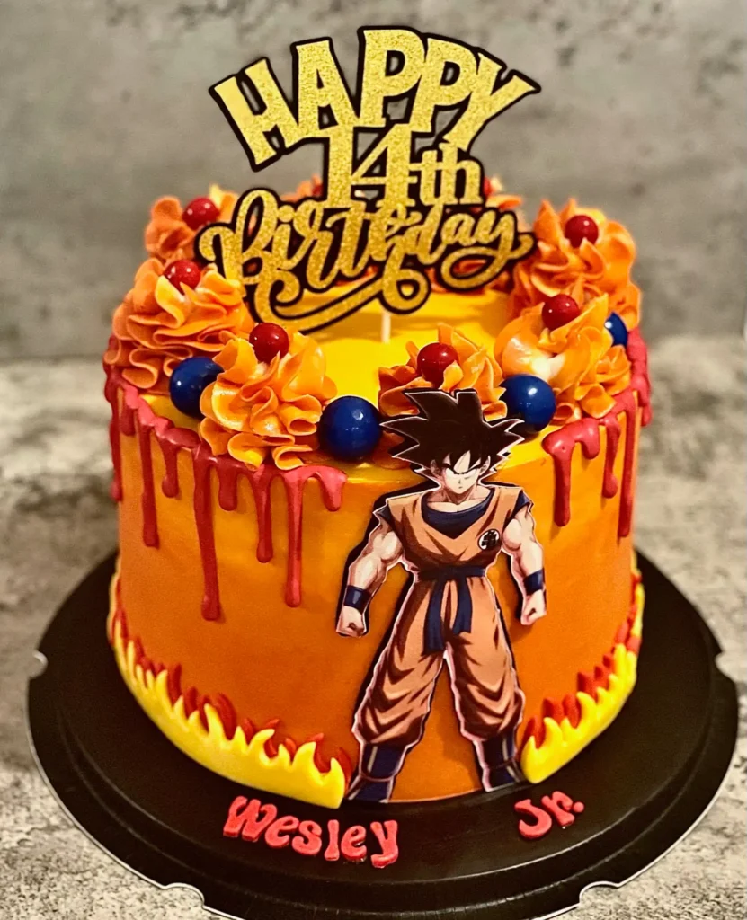 Orange, red, and yellow Dragon Ball Z Goku 14th birthday cake with flame accents, red drip effect, and vibrant piped swirl details — kids birthday cakes Miami by Luxe Layers Cakery