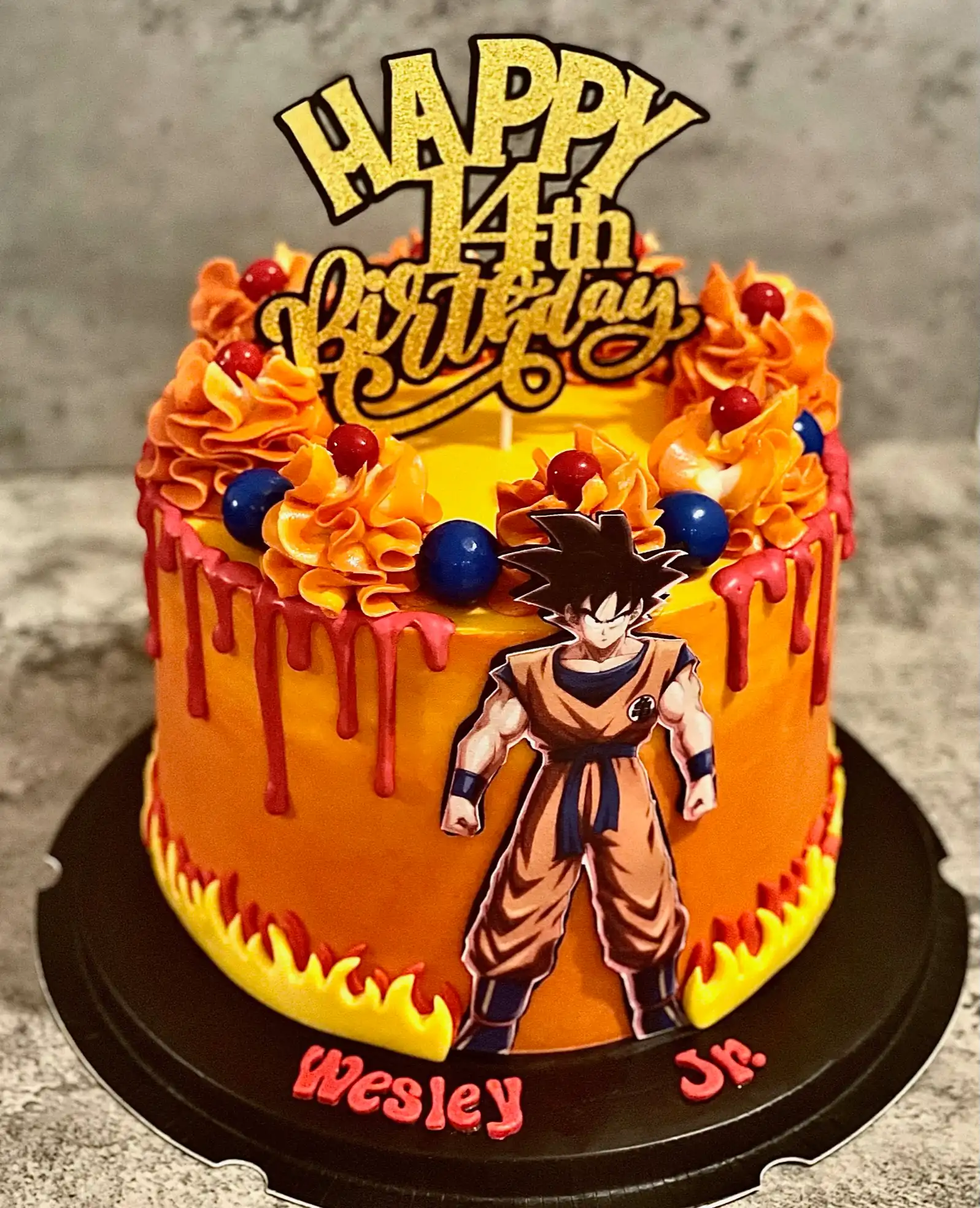 Orange, red, and yellow Dragon Ball Z Goku 14th birthday cake with flame accents, red drip effect, and vibrant piped swirl details — kids birthday cakes Miami by Luxe Layers Cakery