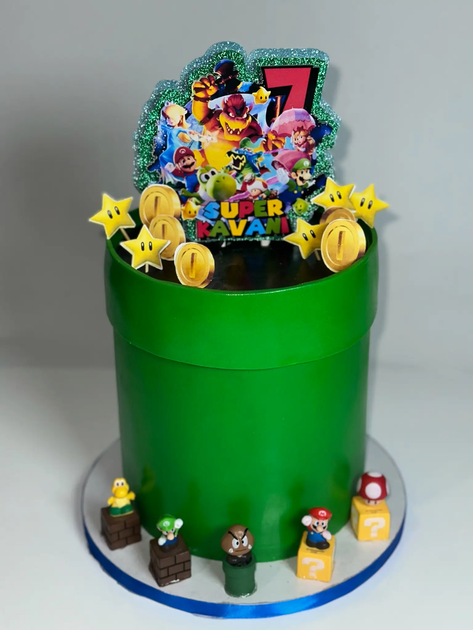 Green and gold Super Mario warp pipe 7th birthday cake with character figurines, gold coins, and star accents — kids birthday cakes Miami by Luxe Layers Cakery