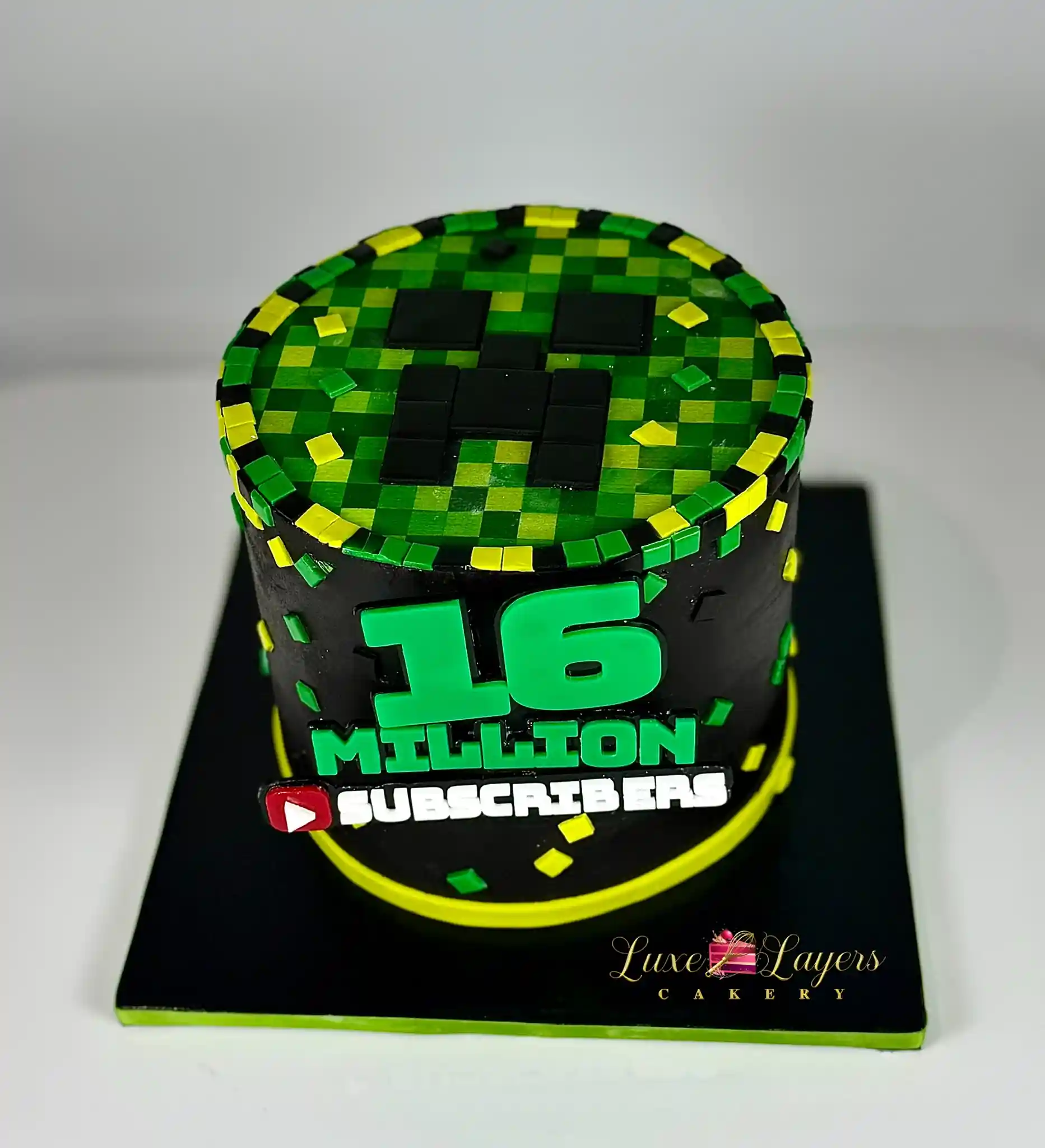 Top-down view of a pixel-patterned custom cake with a creeper-style face design, made for a 16 million subscriber milestone celebration, by Luxe Layers Cakery Miami.