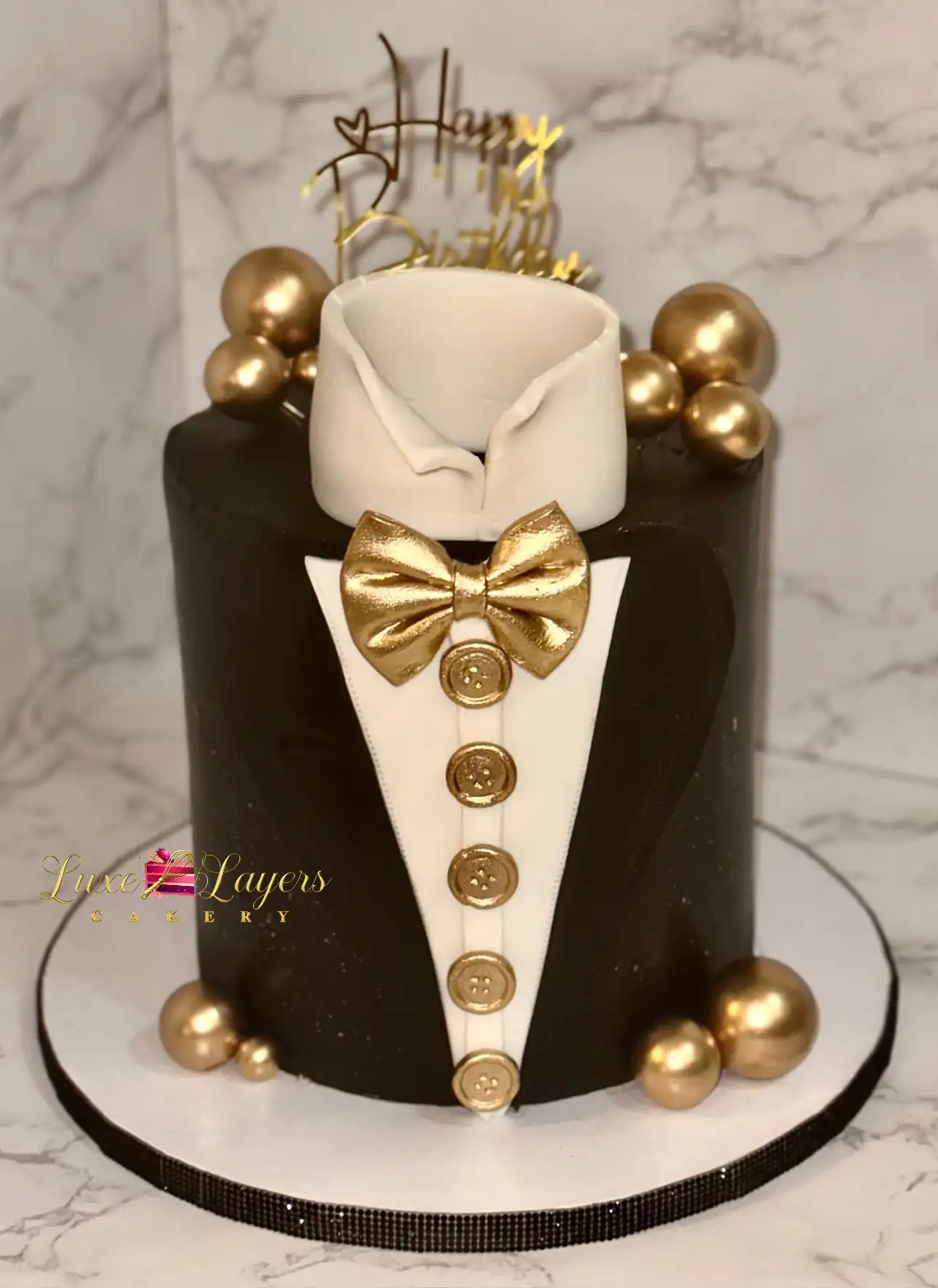 Black and gold tuxedo-inspired birthday cake with gold sphere accents, custom cake by Luxe Layers Cakery